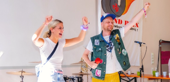 Ehrenamtliche moderieren ein Programm auf der Bühne.