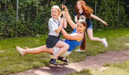 Kinder schaukeln zusammen auf einer Seilschaukel.