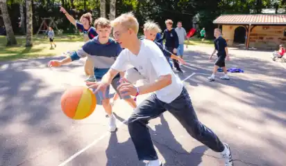 Kinder spielen mit einem Ball auf dem Sportplatz.