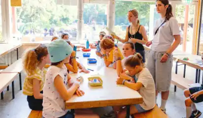 Kinder essen gemeinsam im Speisesaal des Ferienwaldheims.