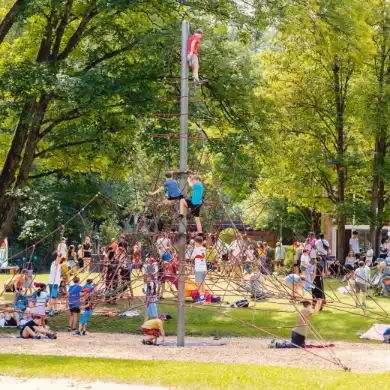 Kinder sitzen bei einer großen Veranstaltung auf einer Wiese.