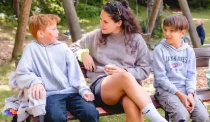 Betreuerin spricht mit zwei Kindern auf dem Gelände.