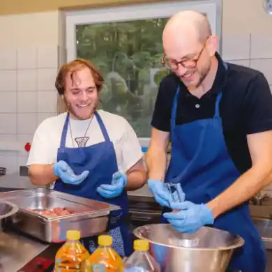 Zwei Ehrenamtliche bereiten Essen in der Waldheimküche zu.