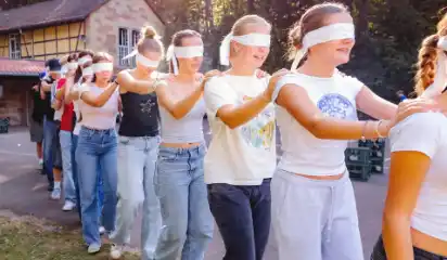 Jugendliche üben ein Vertrauensspiel mit verbundenen Augen.