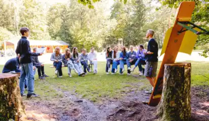 Ausbilder spricht mit Jugendlichen bei einer Schulung im Wald.